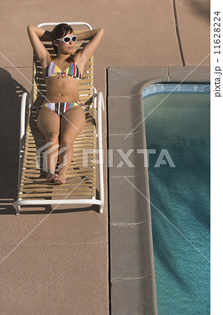 Hispanic woman sunbathing next to swimming pool Hispanic woman sunbathing next to swimming pool 11628224