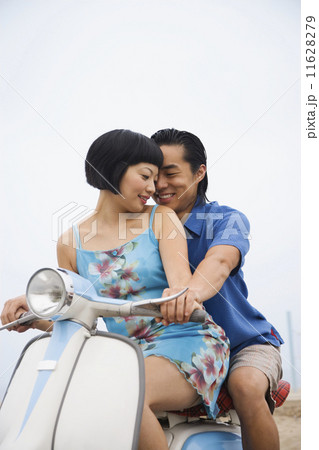 Asian couple sitting on motor scooter Asian couple sitting on motor scooter 11628279