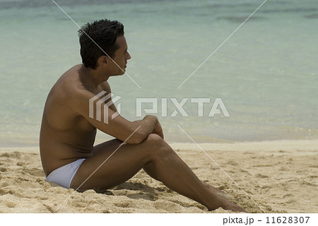 Hispanic man sitting on beach 11628307