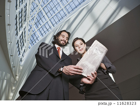 Hispanic businesspeople looking at newspaper Hispanic businesspeople looking at newspaper 11628323