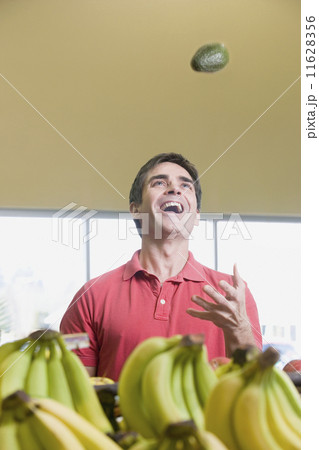 Man juggling avocados at grocery store 11628356
