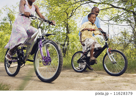 African grandfather teaching grandson to ride a bicycle in park 11628379