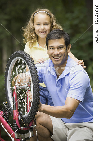Hispanic father fixing daughter's bicycle 11628383