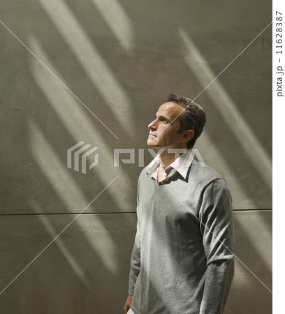 Man looking up into light next to wall Man looking up into light next to wall 11628387