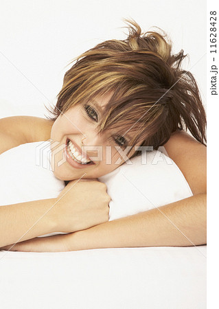 Woman laying with arms around pillow Woman laying with arms around pillow 11628428