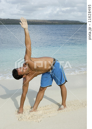 Hispanic man practicing yoga at beach 11628495