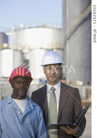 Multi-ethnic businessman and construction worker wearing hardhats 11628503