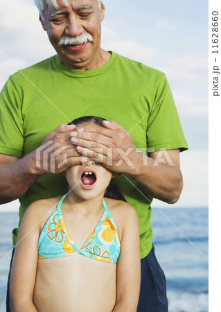 Hispanic grandfather covering granddaughter's eyes 11628660