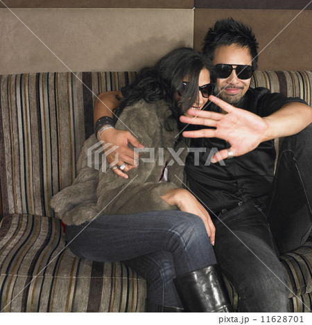 Multi-ethnic couple with hand up on sofa 11628701