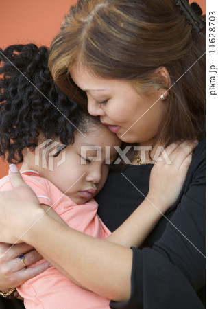 Mother holding sleeping young daughter in arms 11628703