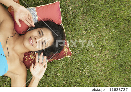 Young woman lying outside listening to music 11628727