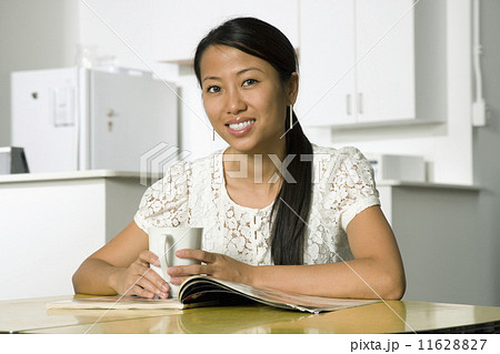 Asian woman holding coffee mug at table 11628827