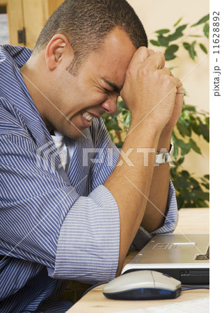 Frustrated Pacific Islander man next to laptop 11628892