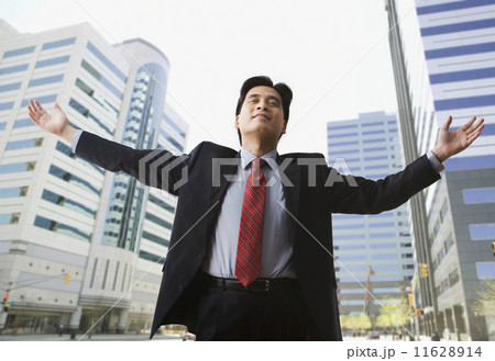 Chinese businessman on city street with arms outstretched Chinese businessman on city street with arms outstretched 11628914