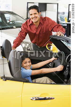 Hispanic father and son looking at new car 11628939