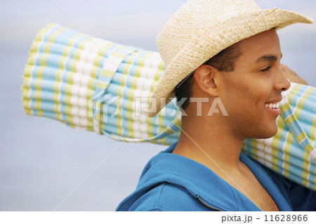 Hispanic man carrying beach mat 11628966