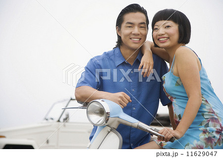 Asian couple sitting on motor scooter Asian couple sitting on motor scooter 11629047