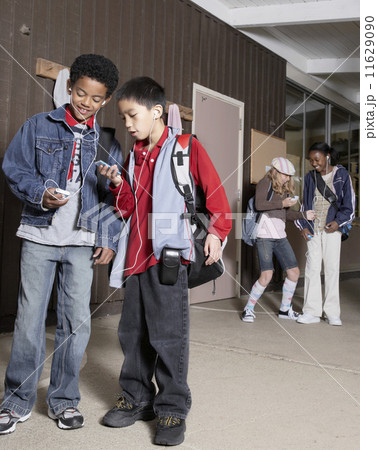Multi-ethnic school children listening to mp3 players 11629090