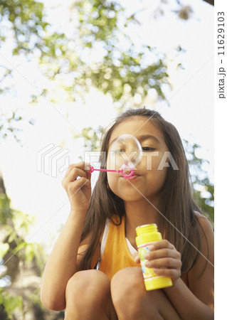 Hispanic girl blowing bubbles outdoors 11629103