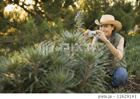 Asian woman taking photograph of plant Asian woman taking photograph of plant 11629143