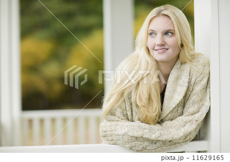 Young woman leaning on porch railing outdoors 11629165