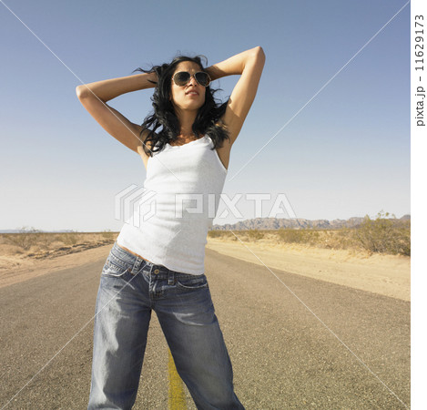 Woman standing in middle of deserted road with hands in hair Woman standing in middle of deserted road with hands in hair 11629173