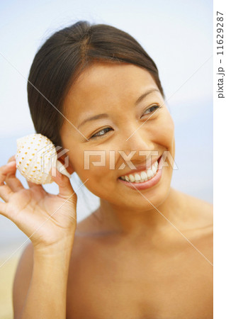Asian woman listening to seashell Asian woman listening to seashell 11629287