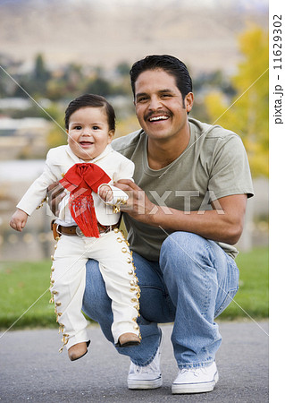 Hispanic father holding baby in costume Hispanic father holding baby in costume 11629302