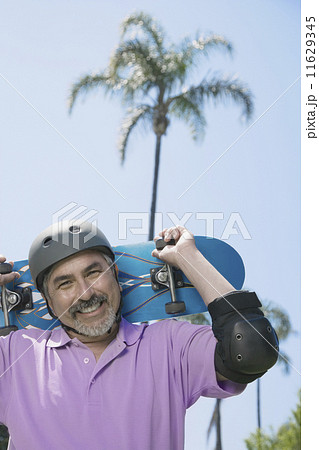 Hispanic man holding skateboard 11629345