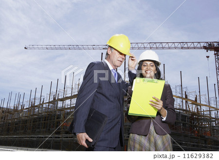 Businesswoman and businessman wearing hard hats at construction site Businesswoman and businessman wearing hard hats at construction site 11629382