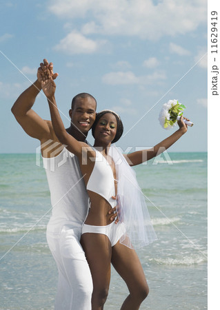 African bride and groom hugging at beach 11629419