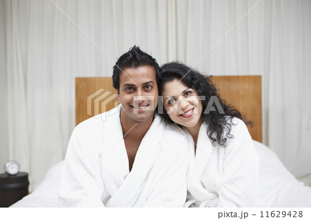 Middle Eastern couple smiling in bathrobes on bed 11629428