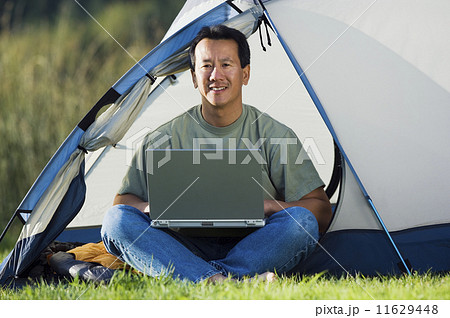 Portrait of man on laptop outside of tent Portrait of man on laptop outside of tent 11629448