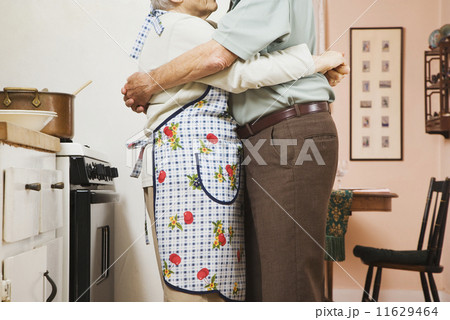 Senior couple hugging in kitchen 11629464