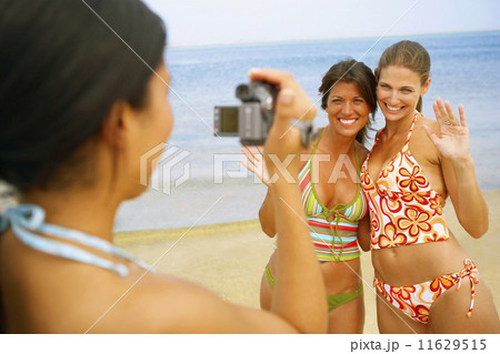 Woman video recording friends at beach Woman video recording friends at beach 11629515