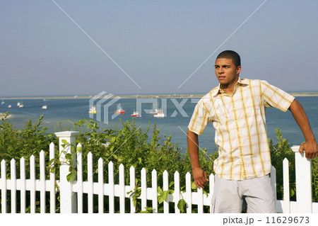 Hispanic man leaning against fence 11629673