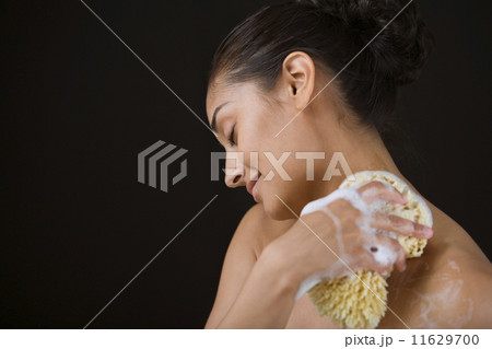 Close up profile of woman bathing with sponge 11629700
