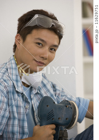 Asian man holding power sander 11629751