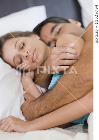 Hispanic couple sleeping in bed 11629794