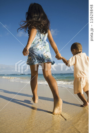 Pacific Islander sister and brother walking on beach 11629848