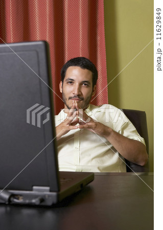 Hispanic man sitting at desk with laptop 11629849