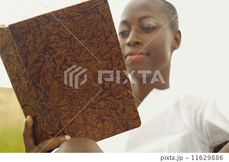 African American woman reading book outdoors 11629886