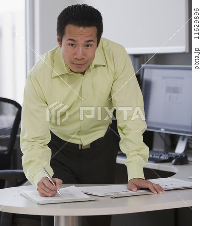 Asian businessman writing at desk 11629896