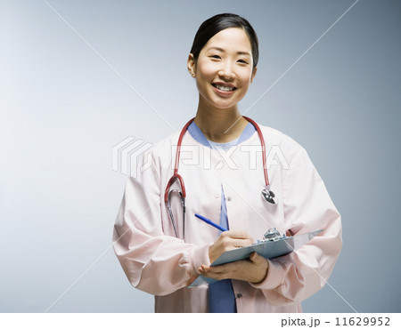 Asian female nurse writing on chart 11629952