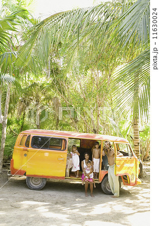 Family posing for the camera with van in tropical setting Family posing for the camera with van in tropical setting 11630024