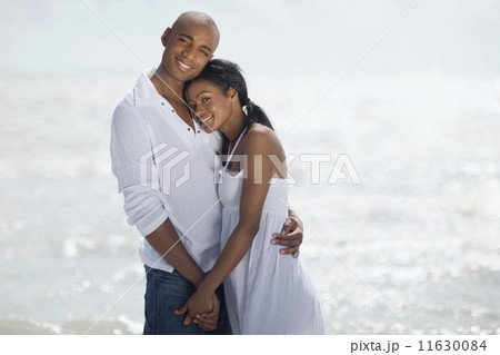 Multi-ethnic couple hugging at beach 11630084