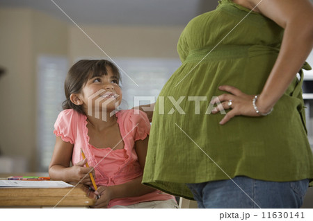 Hispanic girl smiling at pregnant mother Hispanic girl smiling at pregnant mother 11630141