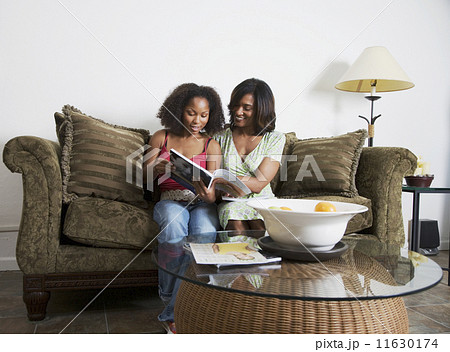 African mother and adult daughter reading magazine African mother and adult daughter reading magazine 11630174