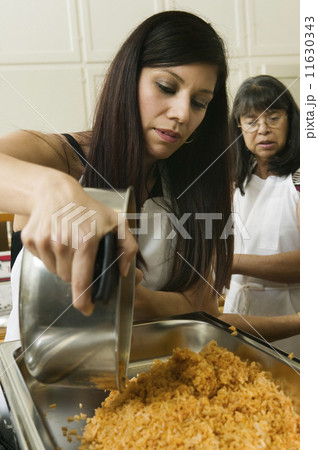 Hispanic woman pouring food into pan Hispanic woman pouring food into pan 11630343