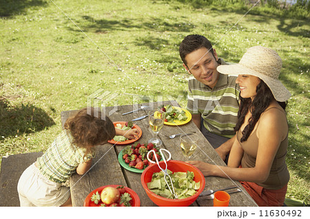 Family eating on a picnic table outdoors Family eating on a picnic table outdoors 11630492